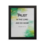 Trust in the Lord and Do Good Psalm 37:3 Bible Verse Wall Art with watercolor green and yellow background. Wall Art hung on the wall in black frame