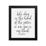 Infidu wall art with the text Like clay in the hand of the potter, so are you in my hand in decorative and standard fonts, black on white background. hung on the wall in a black frame