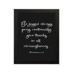 Bible verse wall art featuring 1 Thessalonians 5:16-18 in white cursive text on a solid black background, arranged clearly for easy reading. hung on the wall in a black frame