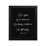 Bible verse wall art with Psalm 115:3 in white text on a black background. Simple and centered design for a bold, modern look. hung on the wall in a black frame