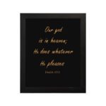 Bible verse wall art with Psalm 115:3 in gold text on a black background. Simple, elegant font centered for easy readability. hung on the wall in a black frame