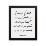 Matthew 22:37 Bible wall art with black text on a white background, featuring Love the Lord your God in cursive letters. hung on the wall in a black frame