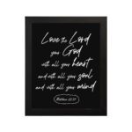 Matthew 22:37 Bible wall art with white text on a black background, reading Love the Lord your God with all your heart. hung on the wall in a black frame