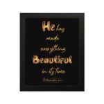 Ecclesiastes 3:11 wall art with golden text on a black background saying He Has Made Everything Beautiful In Its Time. hung on the wall in black frame