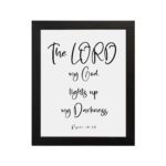 The Lord My God Lights Up My Darkness Psalm 18:28 white text on a black background with a black frame Christian wall art. hung on the wall in a black frame