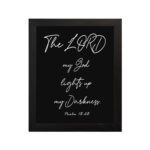 The Lord My God Lights Up My Darkness Psalm 18:28 white handwritten text on black background Christian wall art hung on the wall in a black frame