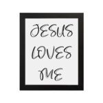 Jesus Loves Me Bible wall art with black script text on a white background. Wall Art hung on the wall in a black frame