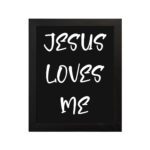 Jesus Loves Me Bible wall art with bold gold text and a decorative gold border on a black background. Wall Art hung on the wall in a black frame