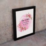 The Lord My God Lights Up My Darkness Psalm 18:28 Bible Verse Wall Art with black text on a soft pink watercolor background and delicate floral accents. Wall Art displayed on the wall in a black frame