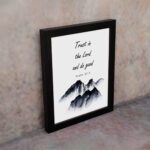 Infidu Trust In The Lord And Do Good Psalm 37:3 Bible Wall Art with black text and mountain illustration. Wall Art displayed on the wall in a black frame