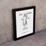 Infidu My Hope Is In You Lord Psalm 39:7 Bible Wall Art with a minimalist line drawing of figure in prayer and clean text Wall Art displayed on the wall in a black frame