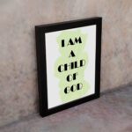 Infidu I Am A Child Of God Bible Wall Art with light green shape and black text on a white background Wall Art displayed on the wall in a black frame