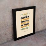 Psalm 50:15 Bible Wall Art with bold black, orange, and yellow text and simple floral embellishments on a cream background. Wall Art displayed on the wall in a black frame