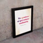 The Goodness Of God Endures Continually Psalm 52:1 Christian Wall Art with bold black and red text on a light cream background. Wall Art displayed on the wall in a black frame