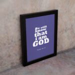 Be Still and Know That I Am God Psalm 46:10 Christian Wall Art with bold white text on a dark purple background. Wall Art displayed on the wall in a black frame