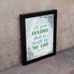 Isaiah 54:13 Christian wall art with blue sky background and leaf designs, featuring the verse All your CHILDREN shall be taught by THE LORD. Wall Art displayed on the wall in a black frame