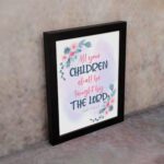 Christian wall art with Isaiah 54:13, featuring 'All Your Children Shall Be Taught By The Lord' in pastel watercolor with floral elements. Wall Art displayed on the wall in a black frame