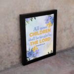 Isaiah 54:13 Christian wall art with vibrant blue and purple floral accents on a soft cream and beige gradient background. Wall Art displayed on the wall in a black frame