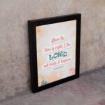 Infidu Isaiah 60:22 Christian wall art with coral and teal text, teal LORD, and a soft pastel watercolor background with floral shapes. Wall Art displayed on the wall in a black frame