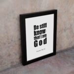 Be Still and Know That I Am God Psalm 46:10 Bible Verse Wall Art with bold black text on a white background. Wall Art displayed on the wall in a black frame