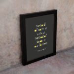 Psalm 46:7 Bible Verse Christian Wall Art - The Lord of Hosts is With Us, Minimalistic Design with Gold Accents. displayed on the wall in a black frame