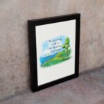 Psalm 46:7 Bible verse wall art with serene watercolor landscape of trees, hills, and water, featuring the verse in black text. displayed on the wall in a black frame