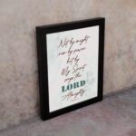 Zechariah 4:6 Christian Wall Art with minimalist design, dark brown text, and teal LORD on a light white floral background. Wall Art displayed on the wall in a black frame