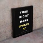 Infidu Your Right Hand Upholds Me Psalm 63:8 Bible Wall Art with black background, yellow, and white font and black from on the wall