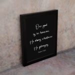 Bible verse wall art with Psalm 115:3 in white text on a black background. Simple and centered design for a bold, modern look. displayed on the wall in a black frame