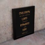 Bible wall art featuring the verse 'Children are a gift from the LORD' in golden text on a black background. displayed on the wall in a black frame