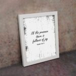 In His Presence There Is Fullness of Joy - Psalm 16:11 Bible Verse Wall Art with Bold Black Text and Distressed Edges on White Background Wall Art displayed on the wall in a white frame