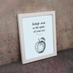 Keep Me As The Apple Of Your Eye Psalm 17:8 Bible Verse Wall Art with light blue background and simple apple sketch. Wall Art displayed on the wall in a white frame