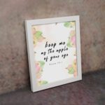 Keep Me As The Apple Of Your Eye Psalm 17:8 Bible Verse Wall Art with apple and leaf design, soft pastel colors, and white background. Wall Art displayed on the wall in white frame