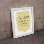 The Lord My God Lights Up My Darkness Psalm 18:28 Bible Verse Wall Art with decorative text on a light yellow paint stroke background. Wall Art displayed on the wall in a white frame