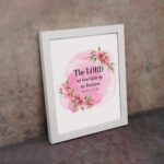 The Lord My God Lights Up My Darkness Psalm 18:28 Bible Verse Wall Art with black text on a soft pink watercolor background and delicate floral accents. Wall Art displayed on the wall in a white frame