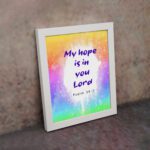 Infidu My Hope Is In You Lord Psalm 39:7 Bible Wall Art with bright blue and pink text and colorful watercolor background Wall Art displayed on the wall in a white frame