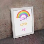 Infidu Jesus Loves Me Bible Wall Art with rainbow arc and colorful text in purple, yellow, and pink fonts Wall Art displayed on the wall in a black frame