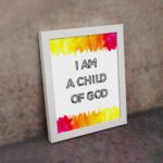 Infidu I Am A Child Of God Bible Wall Art with colorful watercolor borders and black block text on a white background Wall Art displayed on the wall in a white frame