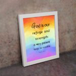 Psalm 46:1 Bible Wall Art with black vertical text on a vibrant rainbow gradient background. Wall Art displayed on the wall in a white frame