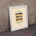 Psalm 50:15 Bible Wall Art with bold black, orange, and yellow text and simple floral embellishments on a cream background. Wall Art displayed on the wall in a white frame