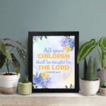 Isaiah 54:13 Christian wall art with vibrant blue and purple floral accents on a soft cream and beige gradient background. Wall Art displayed on the table in a black frame