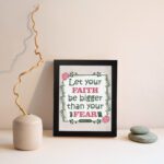 Infidu Let Your Faith Be Bigger Than Your Fear Hebrews 13:6 Christian wall art with floral border on light beige background. Wall Art displayed on the wall in a black frame