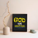 God Will Provide Christian wall art with bold yellow text and a dark black background, perfect for home decor. Wall Art displayed on the wall in a black frame