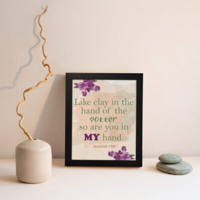 Infidu Jeremiah 18:6 Christian wall art with green and purple text on a light beige background, decorated with purple flowers in the corners. Wall Art displayed on the wall in black frame