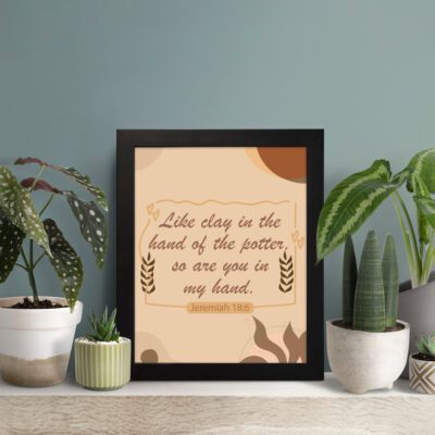 Infidu Jeremiah 18:6 Christian wall art with cursive brown text on a beige background, flanked by wheat stalks and pottery silhouettes. Wall Art displayed on the table in a black frame