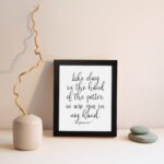 Infidu wall art with the text Like clay in the hand of the potter, so are you in my hand in decorative and standard fonts, black on white background. displayed on the wall in a black frame