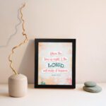 Infidu Isaiah 60:22 Christian wall art with coral and teal text, teal LORD, and a soft pastel watercolor background with floral shapes. Wall Art displayed on the wall in a black frame