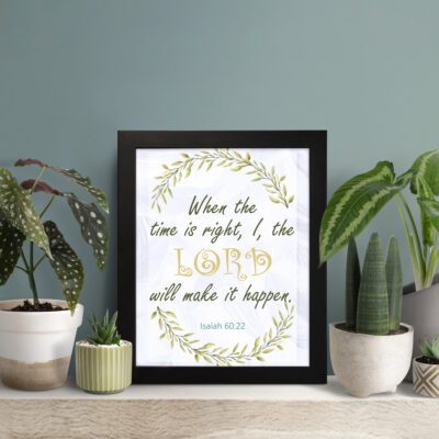 Infidu Isaiah 60:22 Christian wall art with green and gold text, gold LORD, and a wreath of green leaves on a white background. Wall Art displayed on the table in a black frame