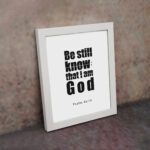 Be Still and Know That I Am God Psalm 46:10 Bible Verse Wall Art with bold black text on a white background. Wall Art displayed on the wall in a white frame