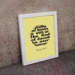 Infidu The Lord Of Hosts Is With Us Psalm 46:7 Bible Verse Wall Art on light yellow background. displayed on the wall in a white frame